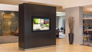 A modern lobby with a digital display, a reception desk, and a seating area. - Courtyard by Marriott Seattle Federal Way (Federal Way)