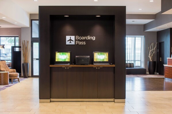 A modern reception desk with a 'Boarding Pass' sign, two monitors, and a laptop.