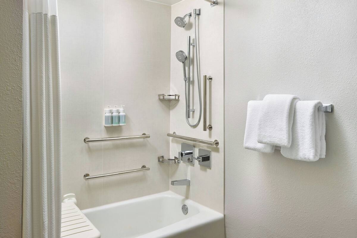 A modern bathroom with a bathtub, shower, and towel rack.