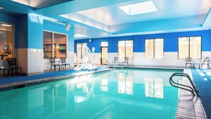 An indoor swimming pool with clear blue water, surrounded by blue walls and windows. - Courtyard by Marriott Seattle Federal Way (Federal Way)