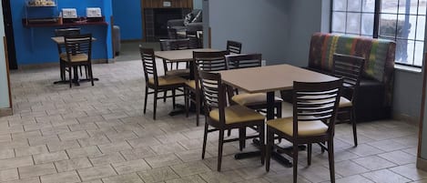 A restaurant with a blue wall, a TV screen, and a seating area with tables and chairs.