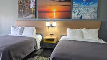 Een hotelkamer met twee bedden, een hoofdbord met wandlampen en drie ingelijste foto’s erboven.
