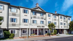A multi-story hotel with a classic facade, a prominent entrance with a red door, and a balcony on the second floor. - Hotel 1550 - SFO Airport (San Bruno)