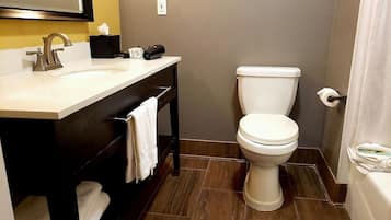 Un baño con lavamanos blanco, tocador negro, inodoro y cortina de ducha.