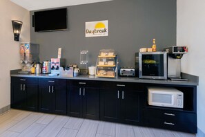 A breakfast area with a flat-screen TV, a microwave, a toaster, and a coffee machine. - Hotel 1550 - SFO Airport (San Bruno)