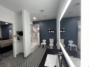 A modern bathroom with a black and white patterned floor, a large mirror, a bathtub, two toilets, and a shower area. - Days Inn by Wyndham Houston-Galleria TX (Houston)