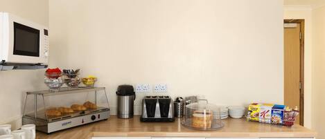 A kitchenette with a microwave, toaster, coffee maker, and a bread display.