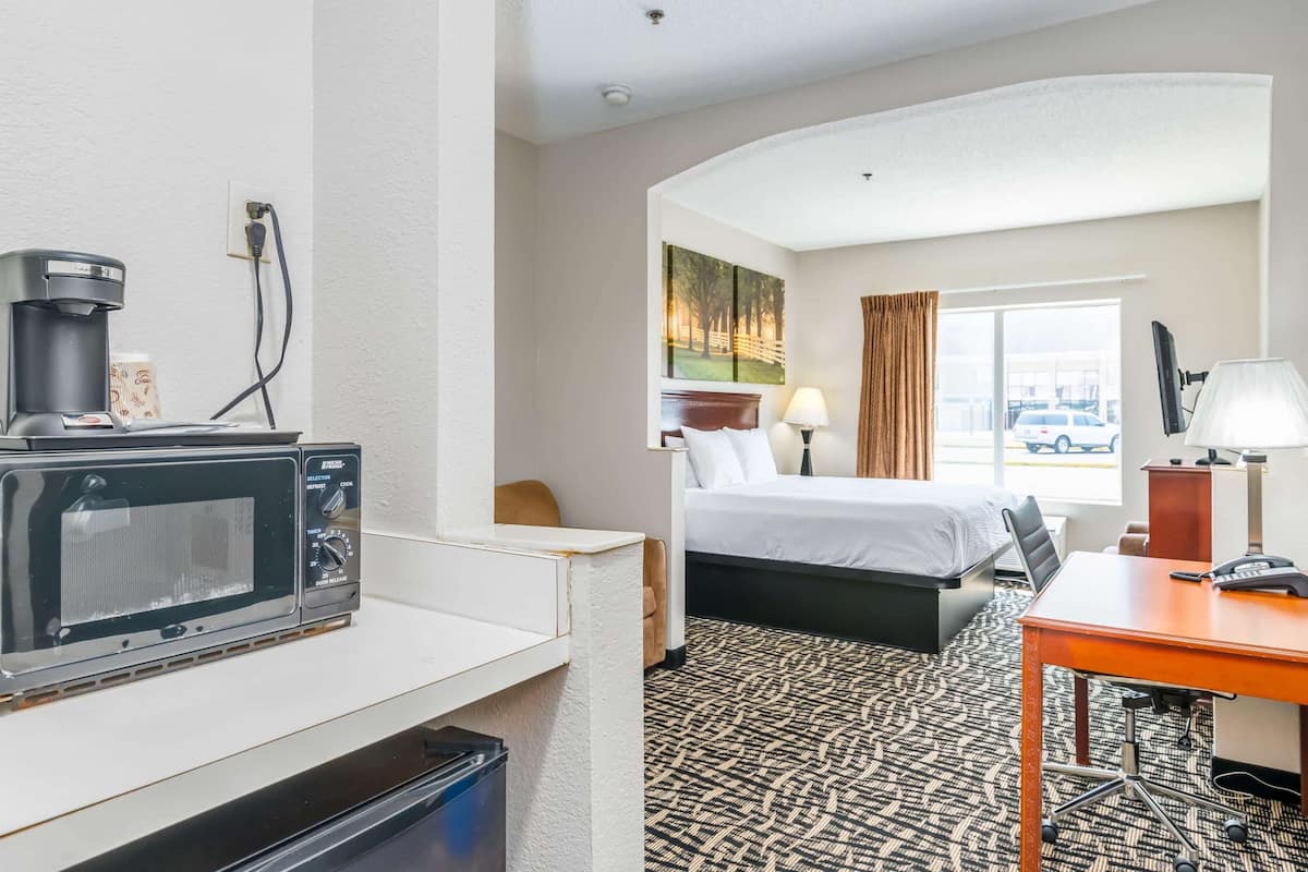A hotel room with a bed, a desk with a computer, a microwave, and a coffee maker.