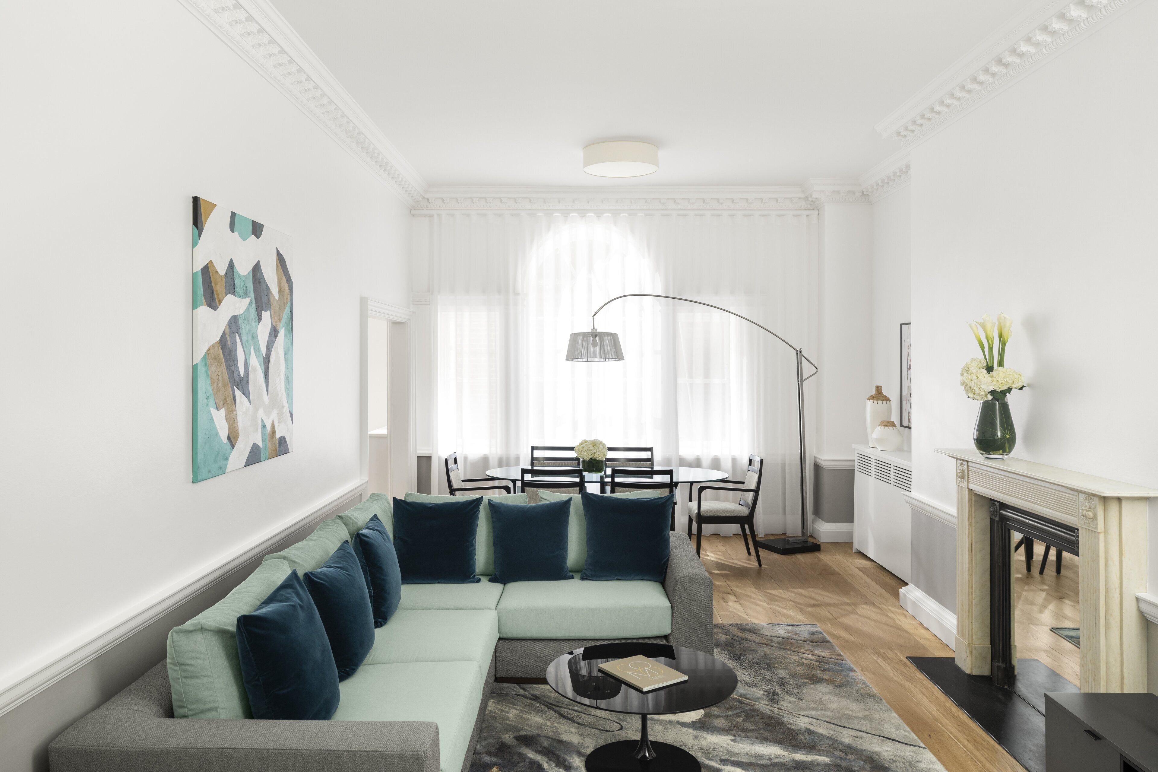 Una sala de estar moderna con un sofá modular, un comedor con mesa redonda y una chimenea.