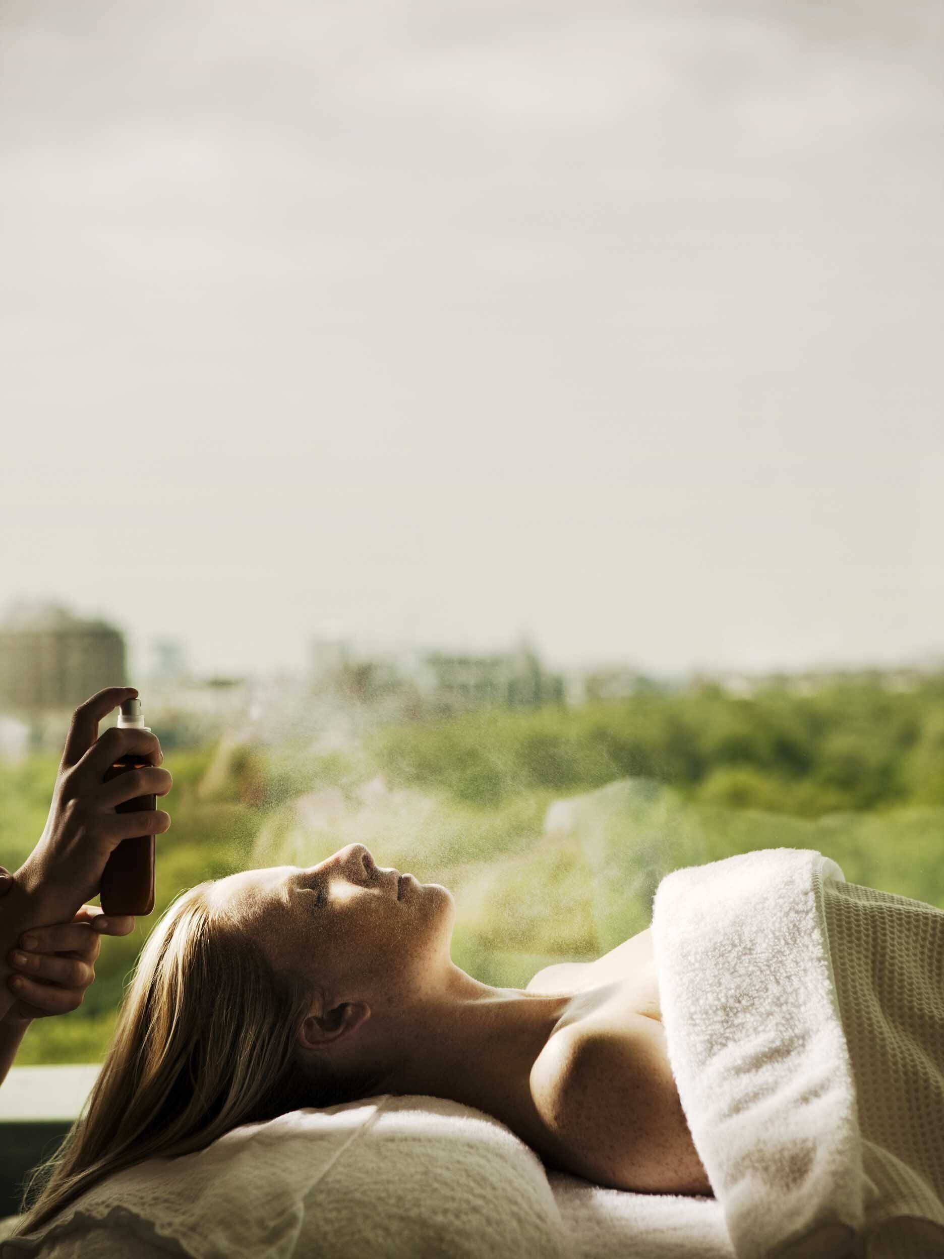 Una persona acostada en la cama con vista a zonas verdes y un paisaje urbano.