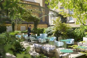An outdoor seating area with tables and chairs, a sofa, and a person walking.