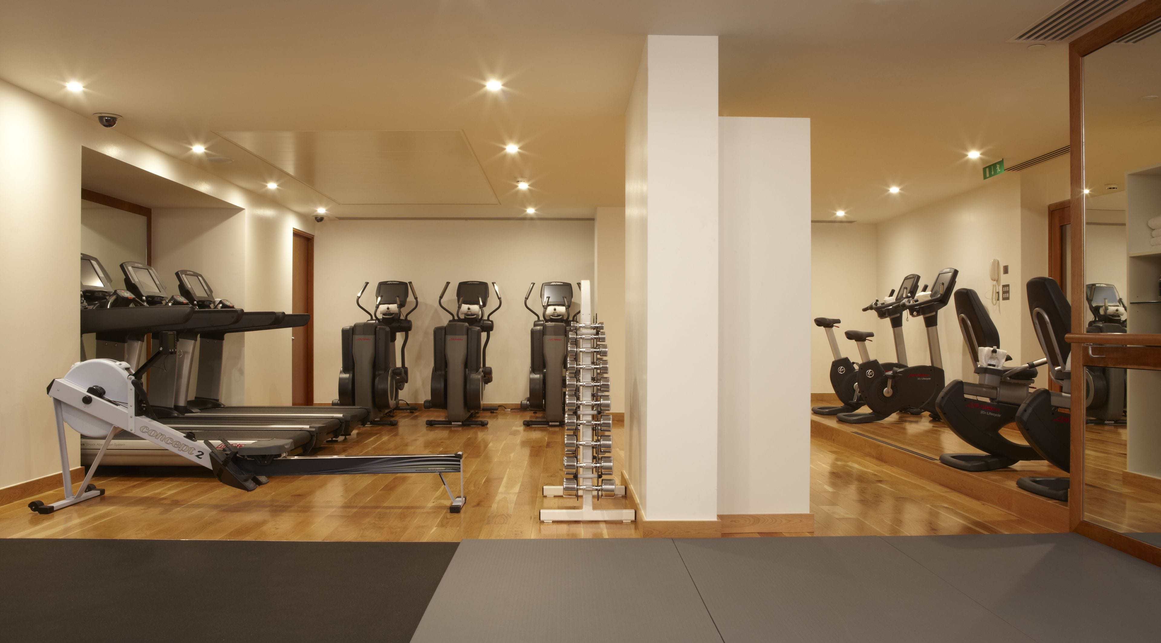 A gym with treadmills, elliptical machines, and a weight rack.