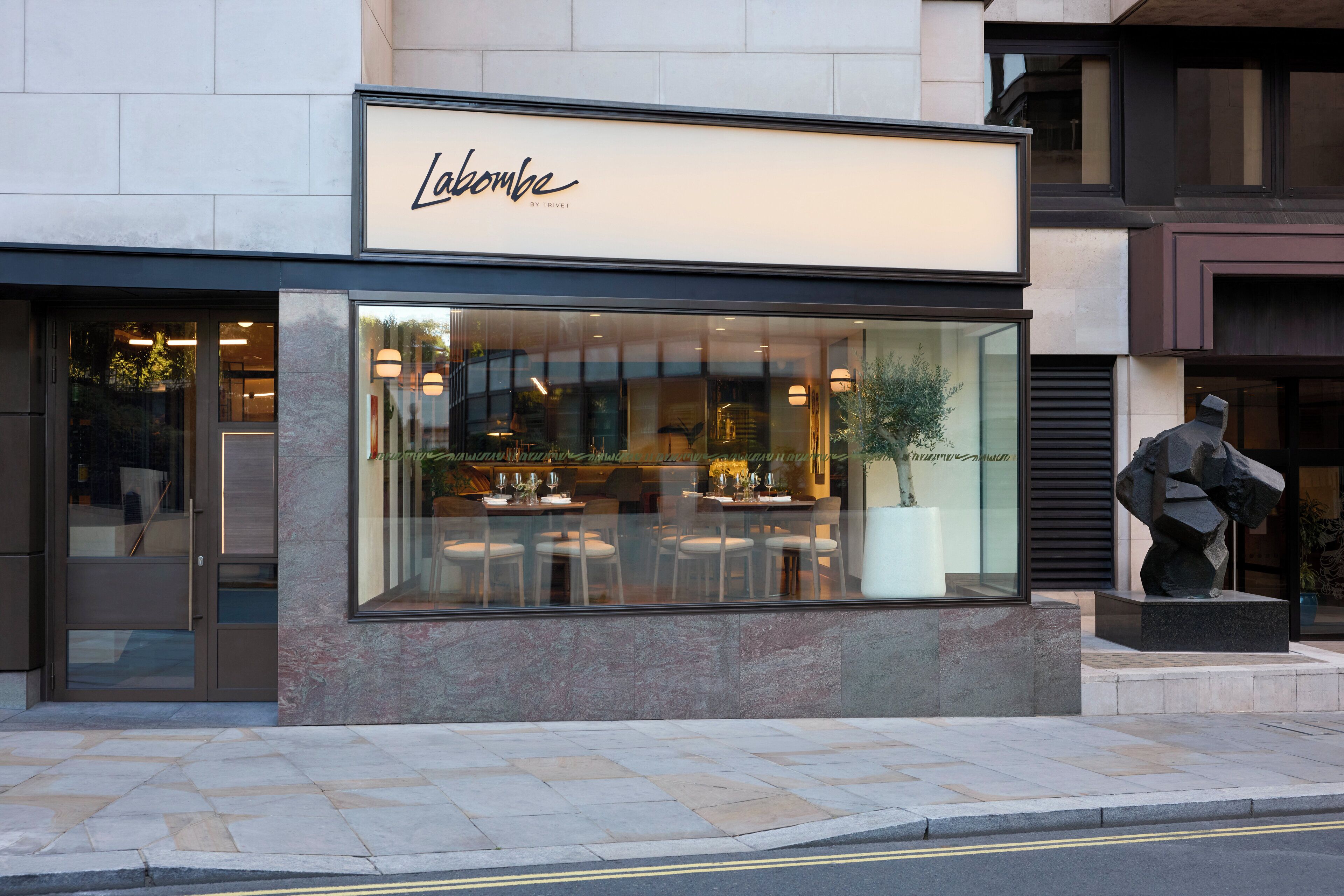 Un bâtiment moderne avec une façade vitrée portant l’inscription « Lambombe by Trivette ».