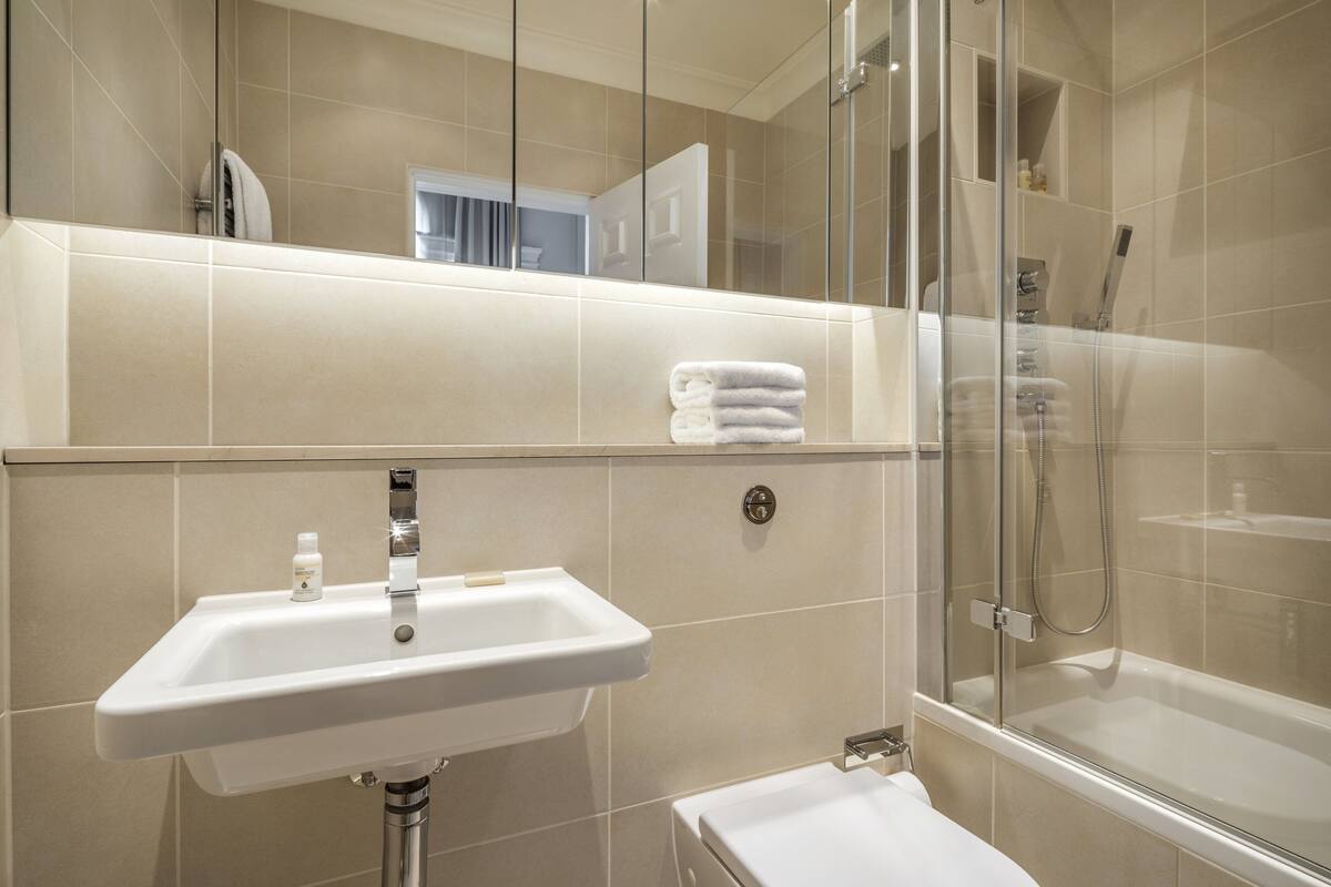 A bathroom with a sink, mirror, and glass-enclosed shower.