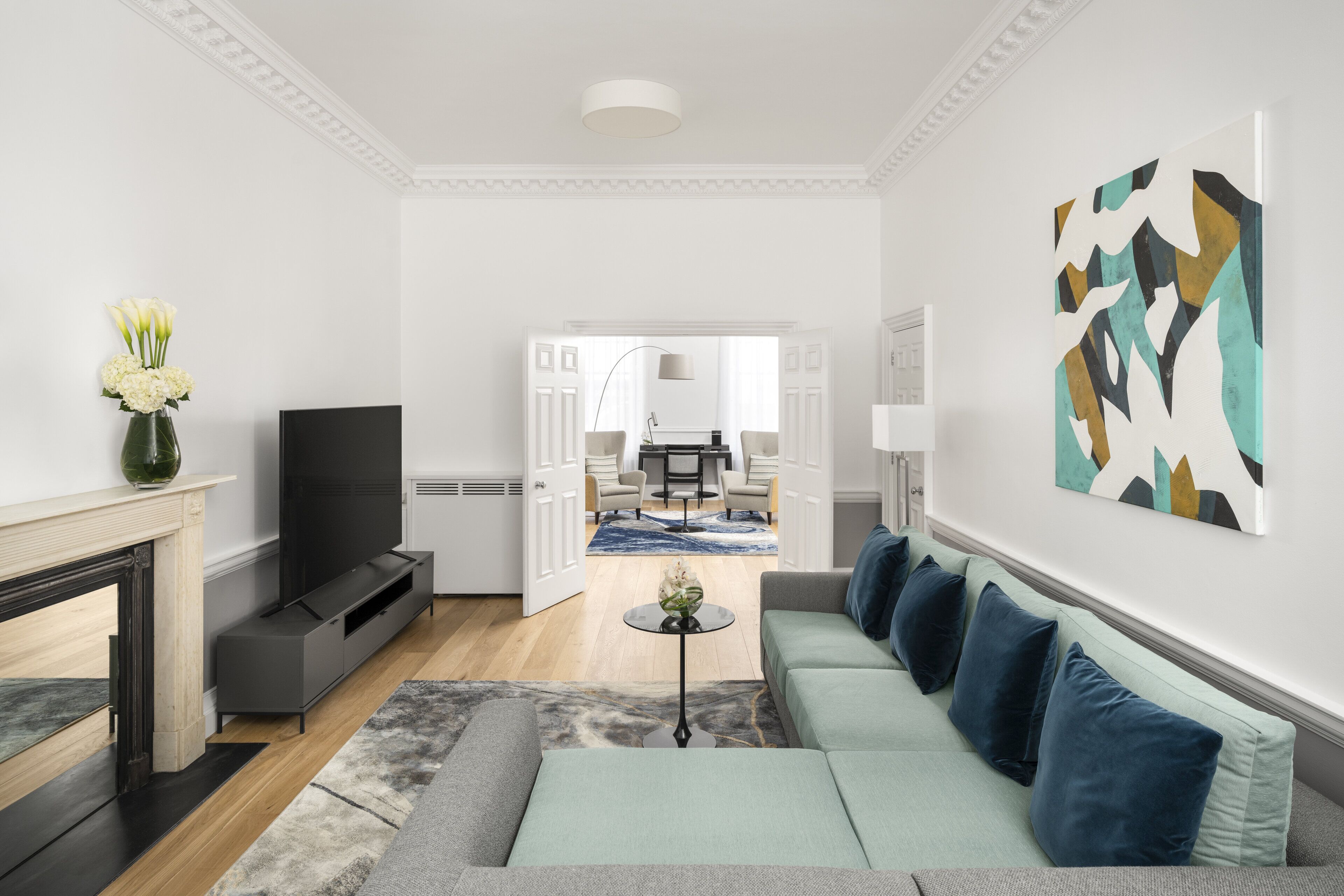 A modern living room with a sofa, a TV, a fireplace, and a dining area in the background.