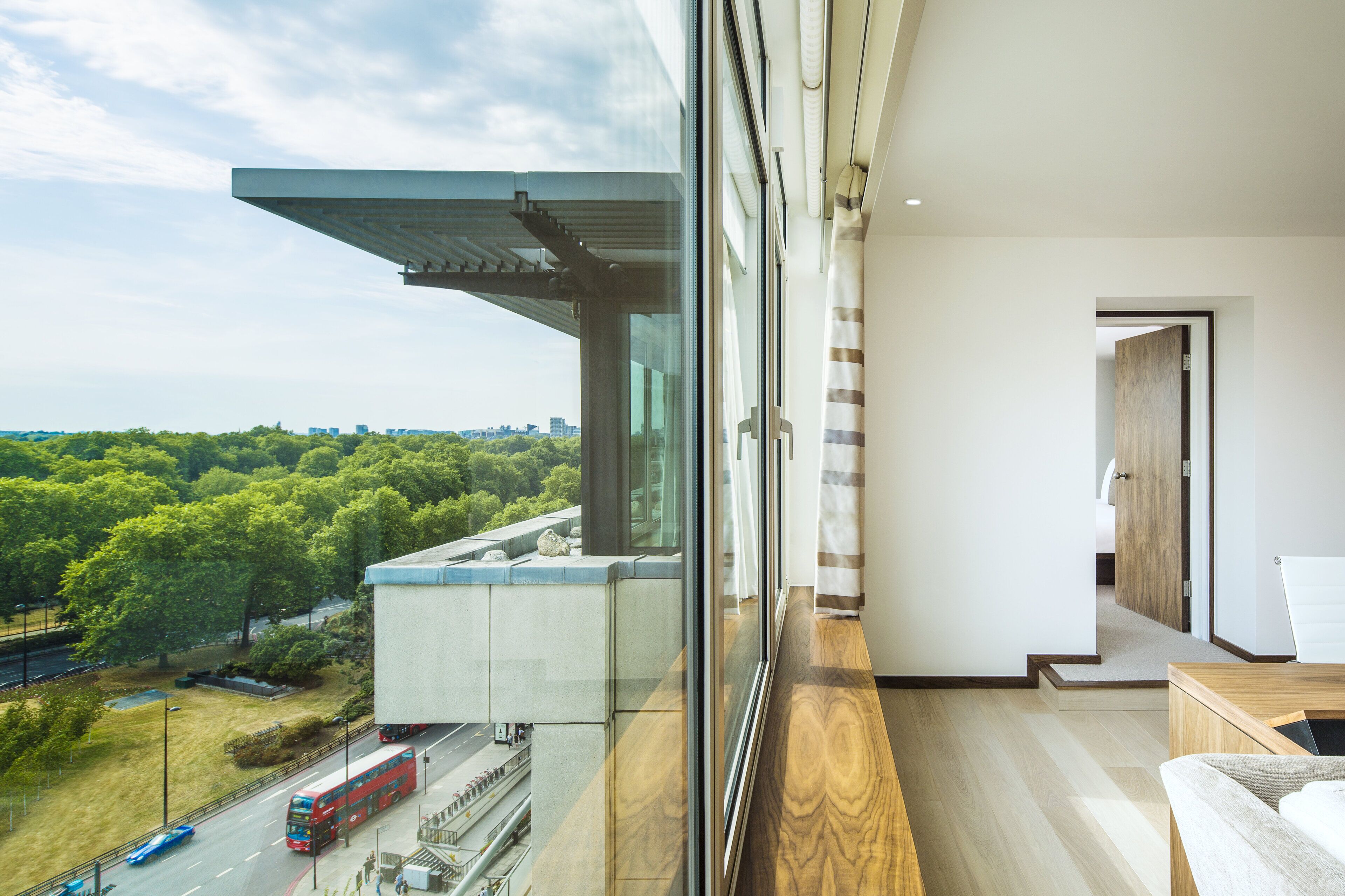 Ein modernes Hotelzimmer mit großem Fenster und Blick auf Stadt und Grünflächen.