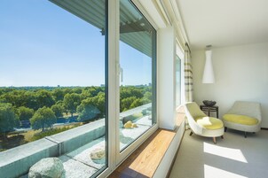 A modern room with a large window offering a city view, two chairs with cushions, and a small table with a bowl.