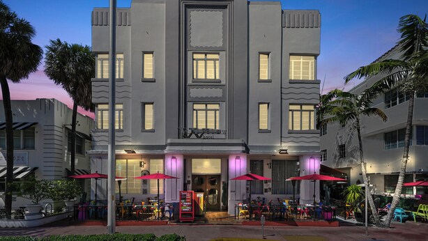 A hotel with a modern facade, multiple windows, and outdoor seating with umbrellas. - The Whitelaw Hotel (Miami Beach)