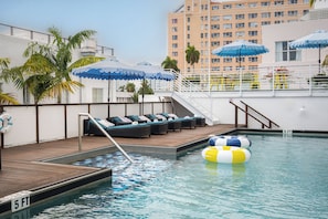 A rooftop pool area with lounge chairs, umbrellas, and a lifebuoy.