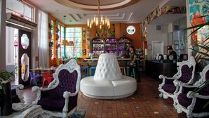 A bar area with a round white table, purple chairs, and a bartender. - The Whitelaw Hotel (Miami Beach)