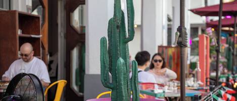 Un cactus en una maceta rosa sobre una mesa afuera de un restaurante.