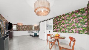 A modern kitchen with a dining area, featuring a round table with chairs, a fruit bowl, and a large window. - The Whitelaw Hotel (Miami Beach)
