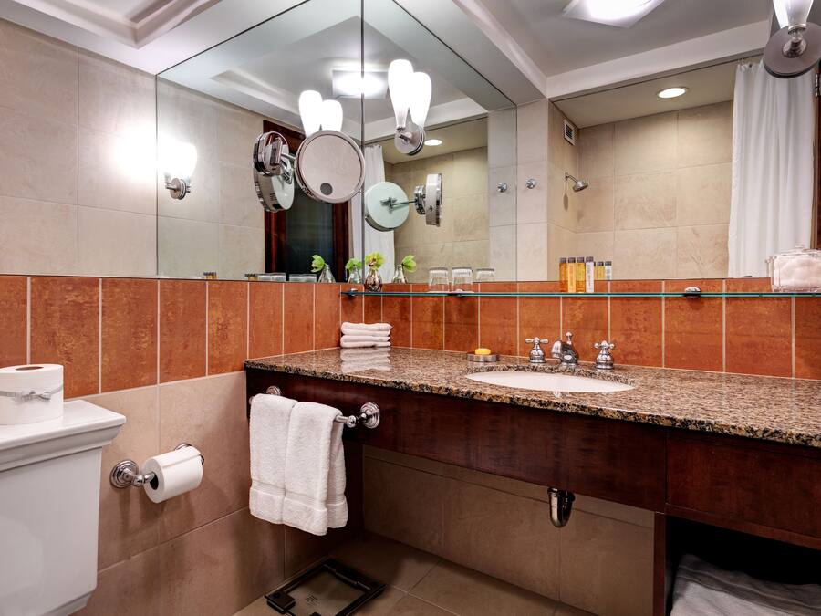 A modern bathroom with a large mirror, granite countertop, and a toilet.