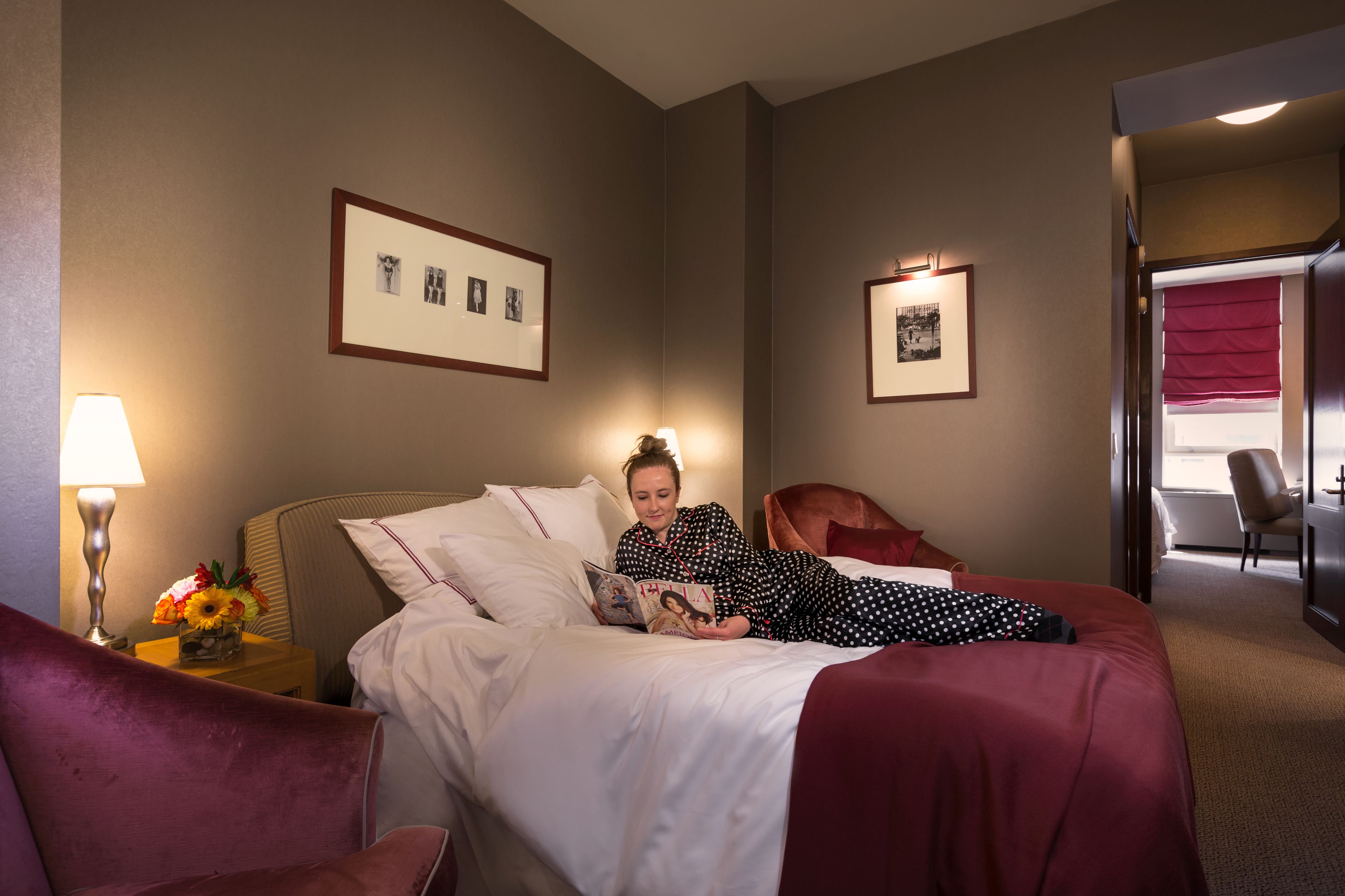 A hotel room with a bed, a chair, a desk, and a lamp.