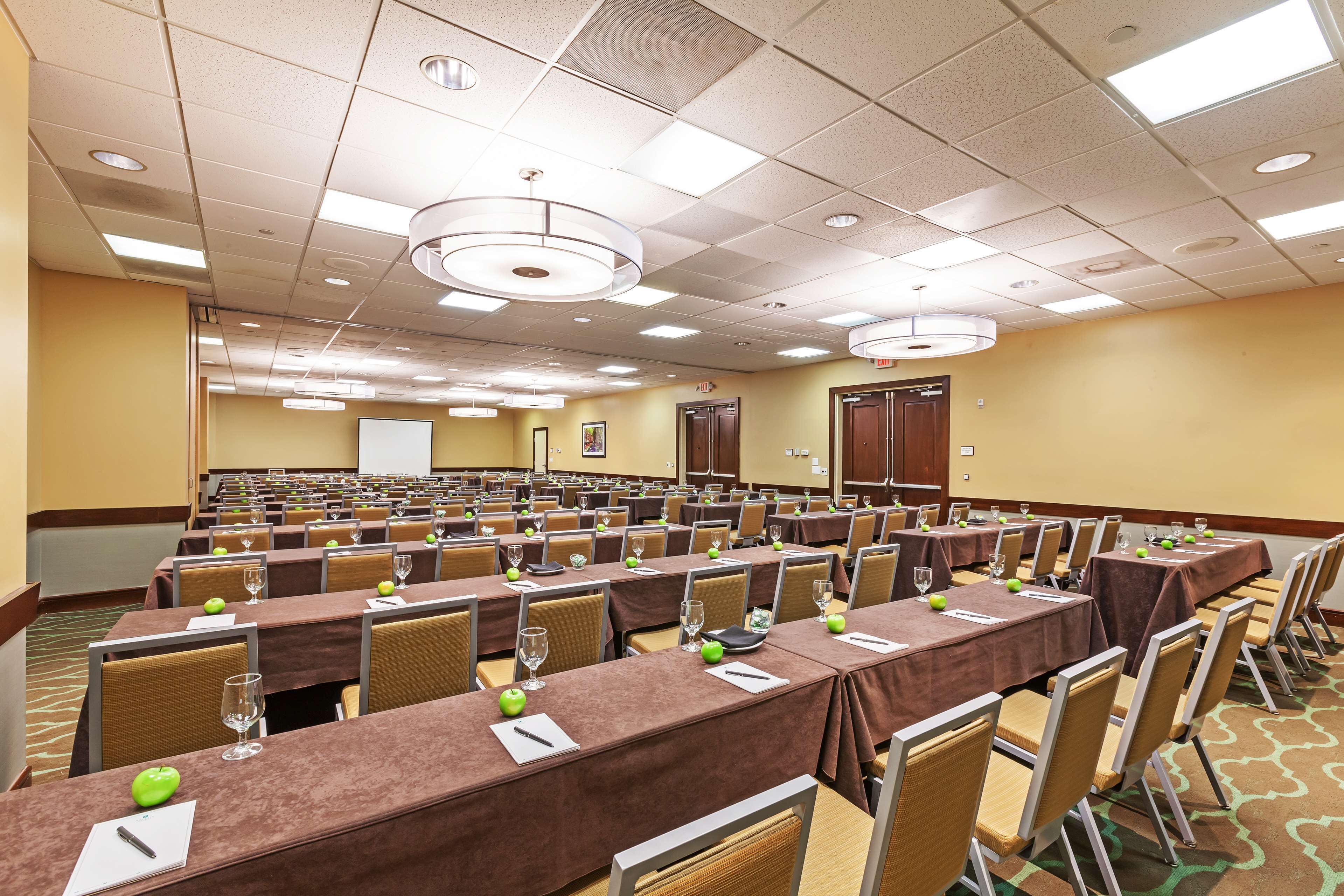 A conference room with rows of tables, chairs, and presentation screens.