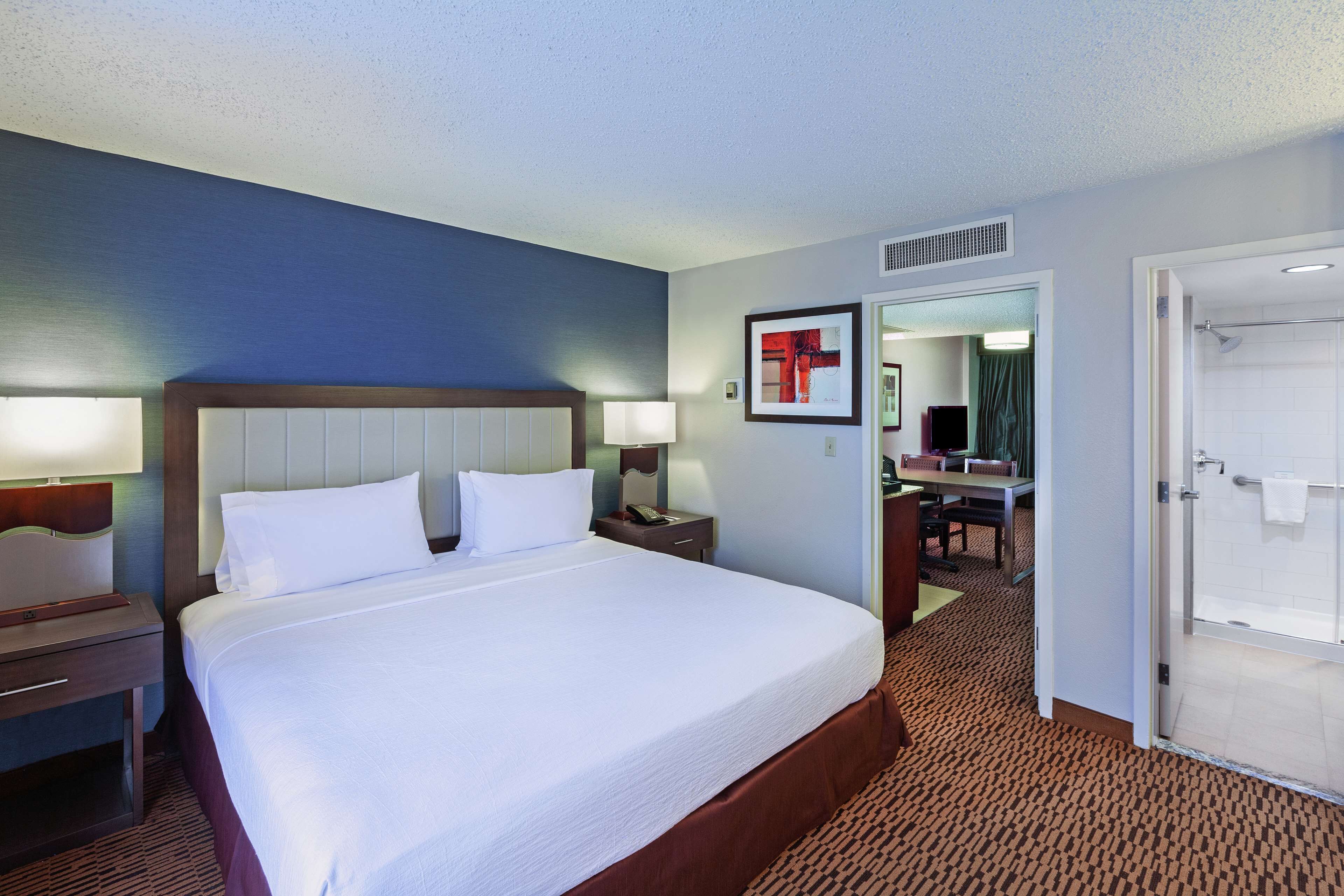 A hotel room with a large bed, bedside tables, a desk, and a bathroom door.