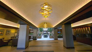 A spacious lobby with a high ceiling, a central chandelier, and a reception desk. - Embassy Suites by Hilton Dallas Market Center (Dallas)