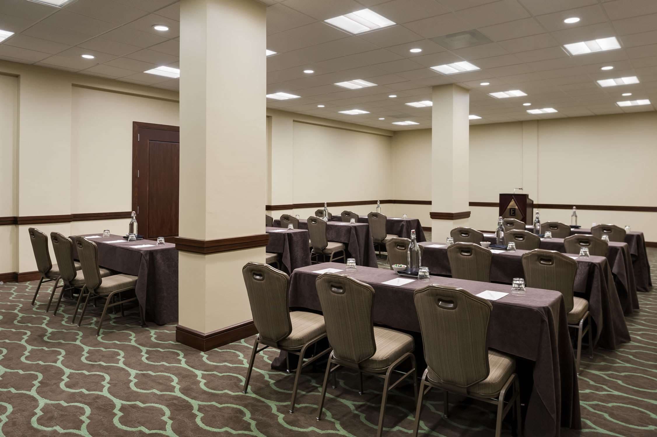 A conference room with multiple tables and chairs, equipped with water bottles and name cards.