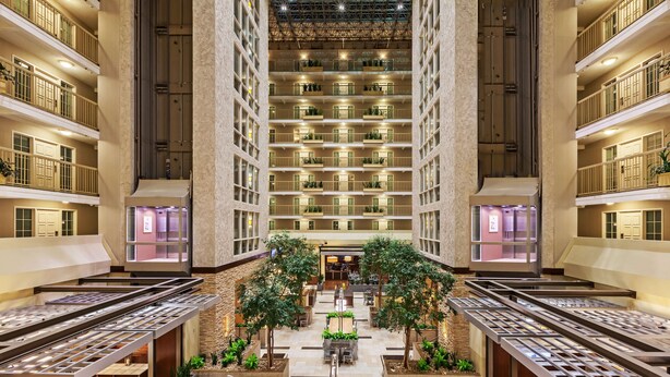 A multi-level hotel atrium with a central courtyard, multiple balconies, and indoor seating areas. - Embassy Suites by Hilton Dallas Market Center (Dallas)