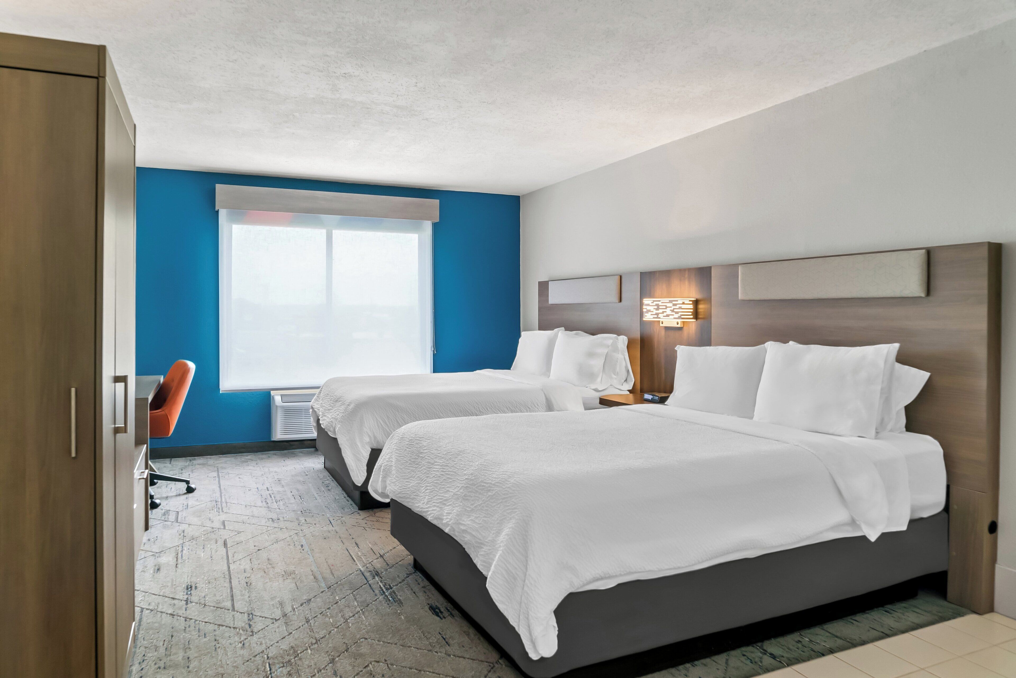 Une chambre d’hôtel avec deux lits, un bureau et une chaise.