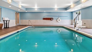 A swimming pool with clear blue water, a ladder, and a lifebuoy on the wall. - Holiday Inn Express Lapeer by IHG (Lapeer)