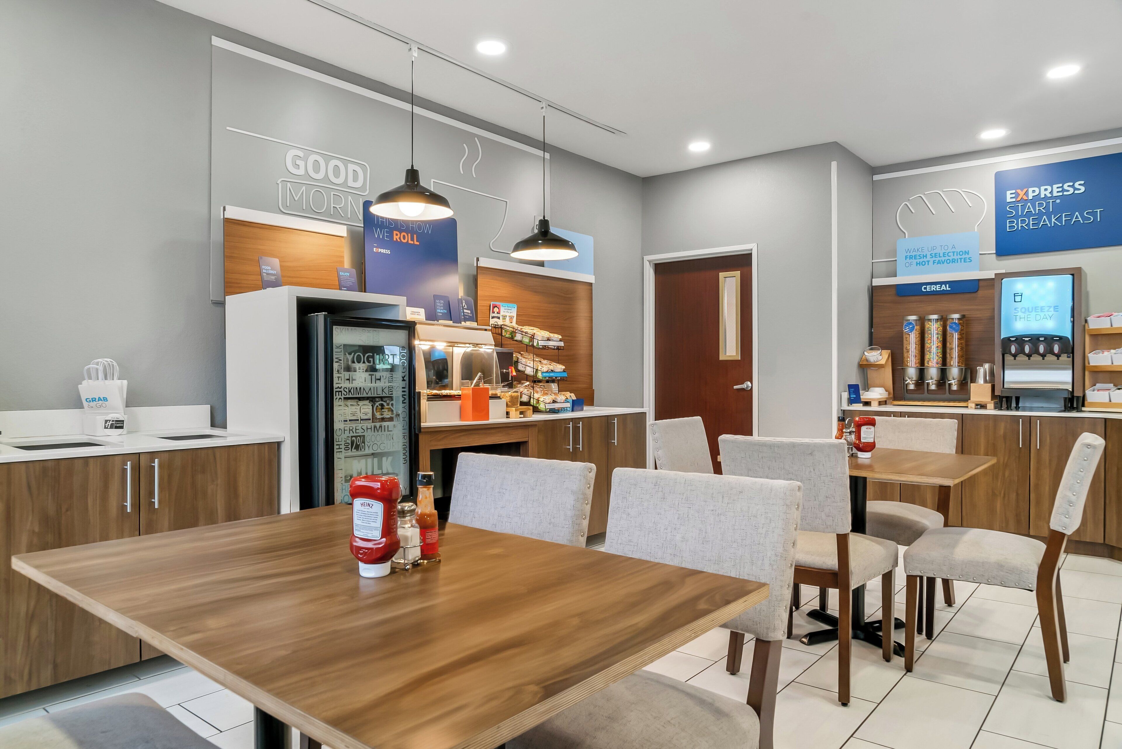 Un moderno comedor con mostrador, asientos y refrigerador.