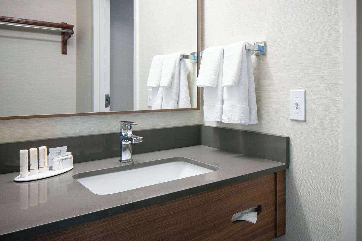 A bathroom with a sink, mirror, and towel rack.