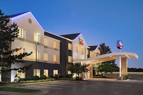 A Fairfield Inn & Suites hotel with a modern design, featuring a well-lit entrance and a parking lot.