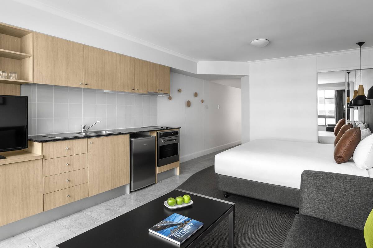 Una habitación de hotel moderna con kitchenette, cama y sofá.
