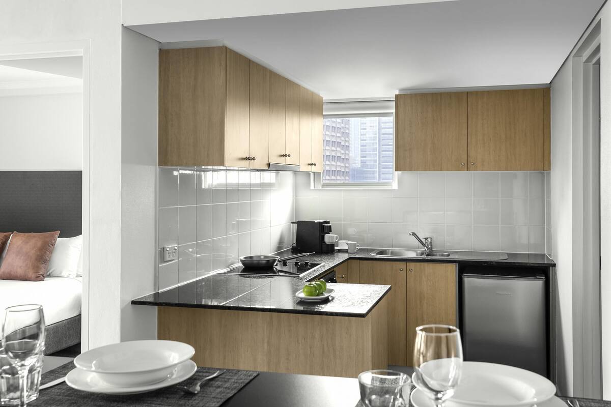Una cocina moderna con armarios de madera, encimera negra y lavavajillas integrado.