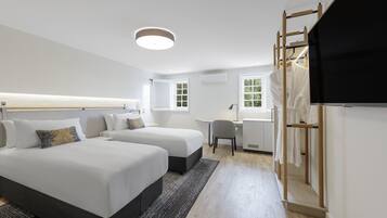 A modern hotel room with two beds, a desk, a chair, and a TV.