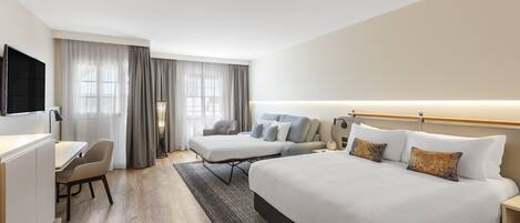 A hotel room with a large bed, a smaller bed, a desk, and a chair.