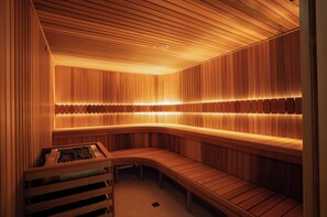 Una sauna con pareti e panche in legno, una panca con un asciugamano e una parete illuminata.