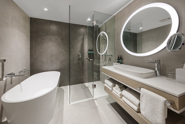 Un baño moderno con una bañera independiente, ducha con mampara de vidrio y un tocador con un espejo grande.