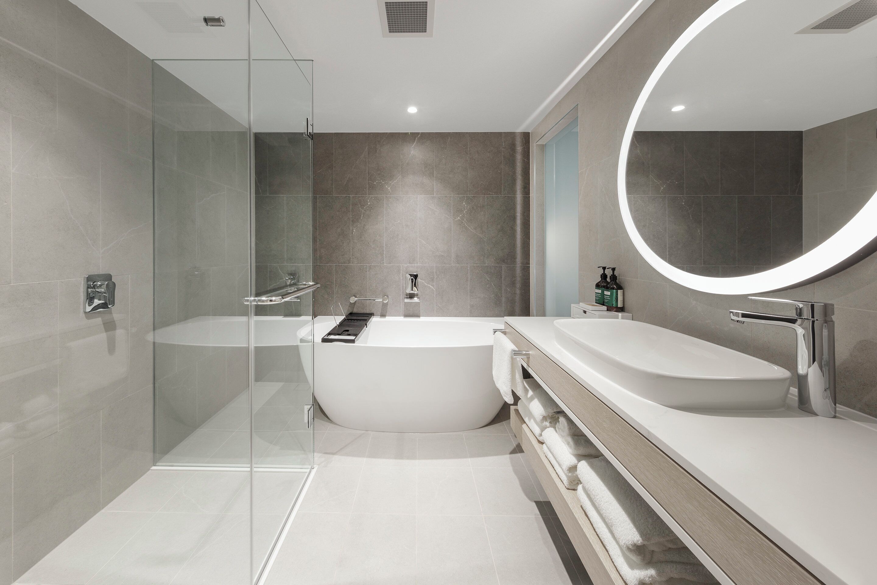 Une salle de bain moderne dotée d’une douche à parois de verre, d’une baignoire sur pieds et d’un meuble-lavabo avec un grand miroir.