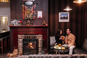 A cozy room with a fireplace, a table with food, and a couple sitting by the fire.