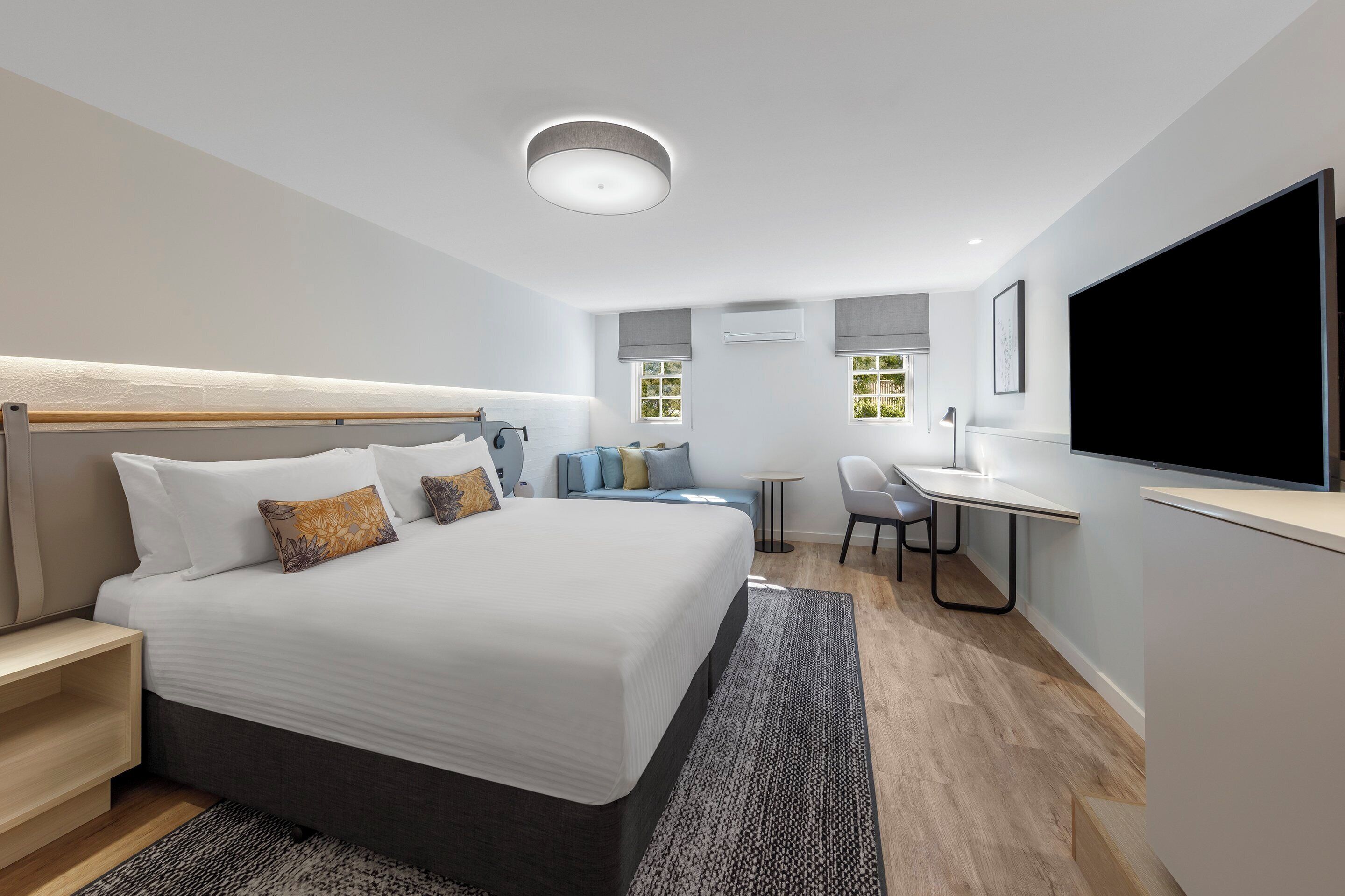 Une chambre d’hôtel moderne avec un grand lit, un bureau et une télévision.