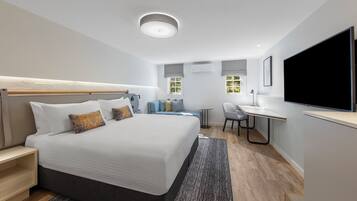 Une chambre d’hôtel moderne avec un grand lit, un bureau et une télévision.