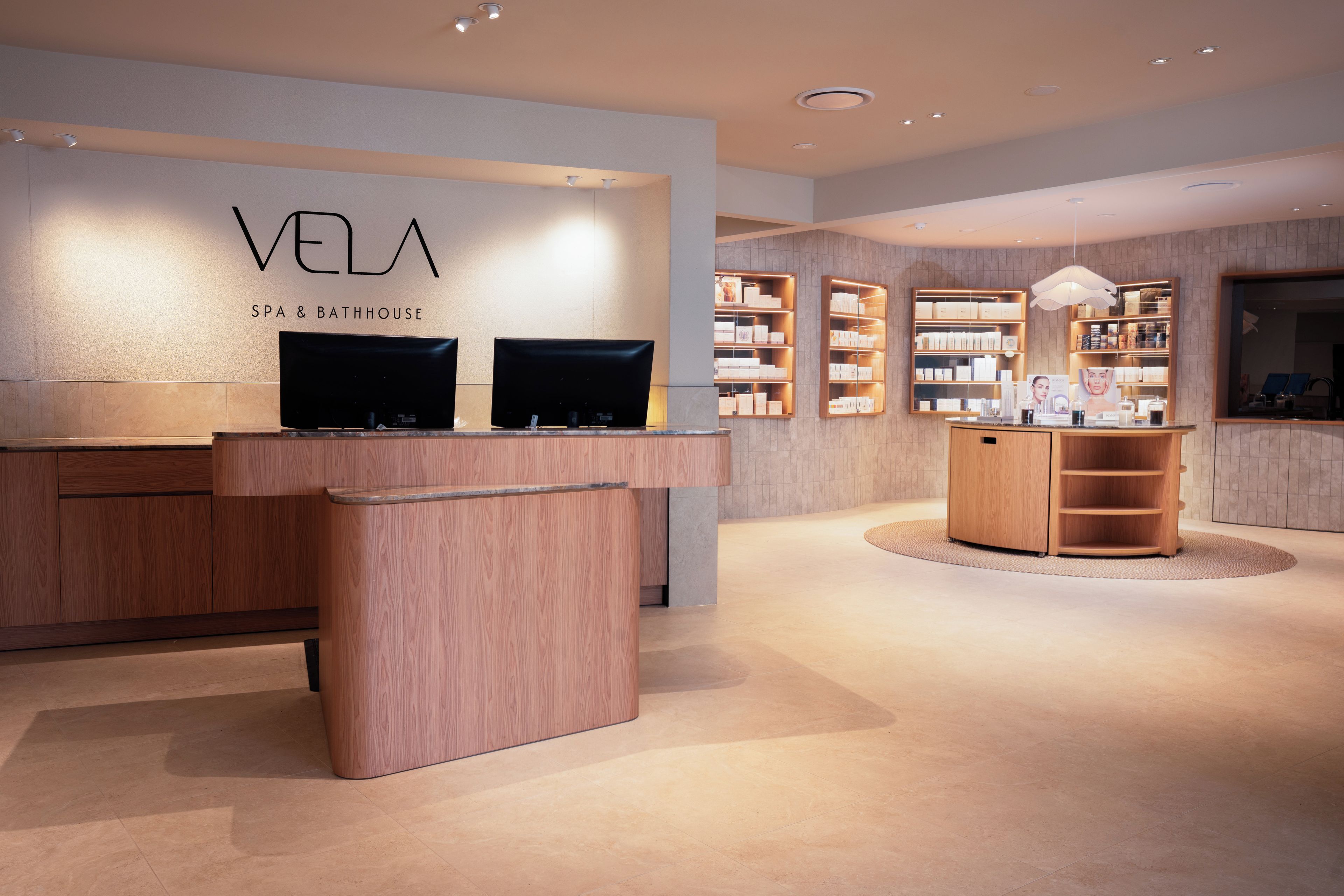 A modern spa and bathhouse interior with a reception desk, shelves with products, and a wooden display unit.