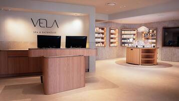 A modern spa and bathhouse interior with a reception desk, shelves with products, and a wooden display unit.